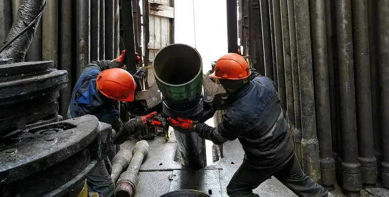 oil and gas workers handling a pipe