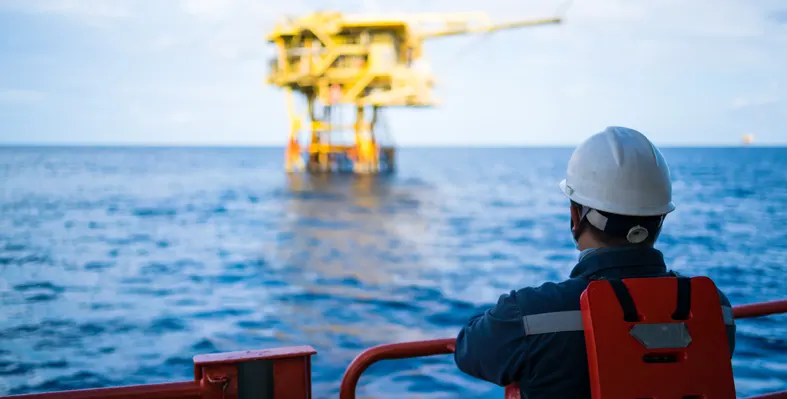 an oil and gas worker looking over the deck at an offshore platform 